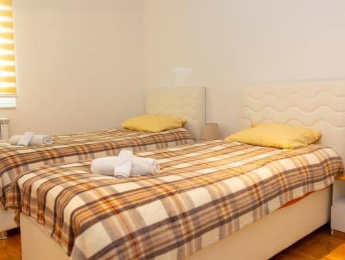 two beds in a bedroom with yellow pillows at VerdeLuxe Sarajevo in Sarajevo