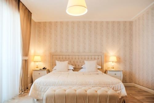 a bedroom with a large white bed with two lamps at Palace Hotel & SPA in Durrës