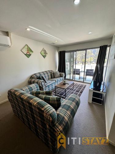 un salon avec deux canapés et une télévision dans l'établissement Tranquil, Relaxing Forrest Style Apartment - Braddon CBD, à Canberra