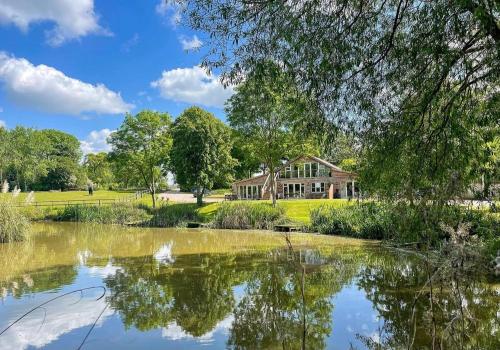une maison avec un étang en face de celle-ci dans l'établissement Warbler Lodge, à Droitwich Spa