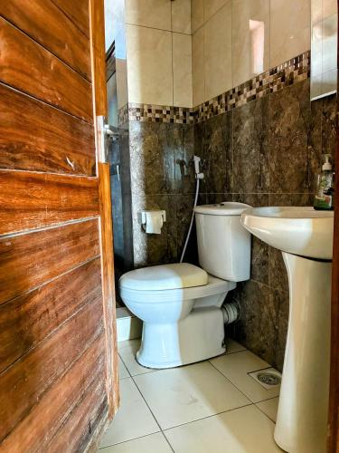 a bathroom with a toilet and a sink at TheGatsbyStyle by EcoPact in Dar es Salaam