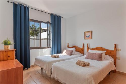 Dos camas en una habitación con cortinas azules. en Villa Timanfaya, en Tías