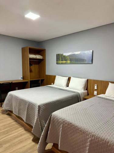 a room with two beds and a tv on the wall at Hotel Premier in Belo Horizonte