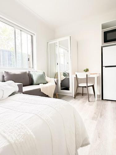 a white bedroom with a bed and a couch at North Wollongong - Beach Style - Modern - Free Parking - Free Coffee Snacks in Woonona