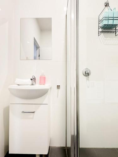 a white bathroom with a sink and a shower at North Wollongong - Beach Style - Modern - Free Parking - Free Coffee Snacks in Woonona