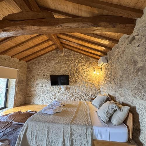 a bedroom with a bed in a stone wall at Gardunha Stone in Louriçal do Campo