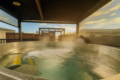 a hot tub with water in it on a patio at Natural Geothermal Hot Spring Retreat Rotorua in Rotorua