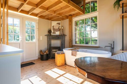 Una sala de estar con bañera, mesa y ventanas. en Le Parc de Louette - Le Pavillon - Esc'Appart, en Gedinne