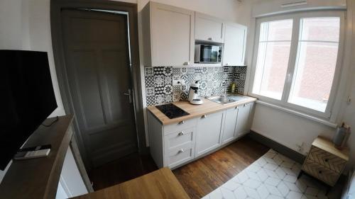 康布雷Studio Tout équipé à Cambrai的厨房配有白色橱柜、水槽和窗户