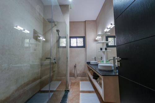 a large bathroom with two sinks and a shower at Villa Dar El Gharrabia in Amezrou