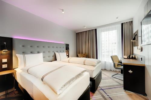 a hotel room with two beds and a desk at Premier Inn Hamburg City Klostertor in Hamburg