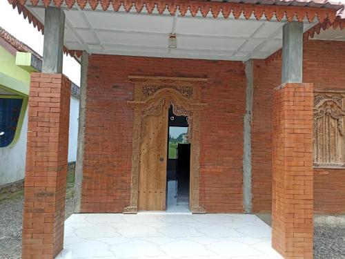 - une entrée pour un bâtiment en briques avec une porte en bois dans l'établissement Joglo Hexa, à Bugisan