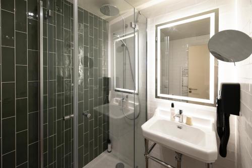 a bathroom with a sink and a shower with a mirror at Hôtel Vacances Bleues Balmoral in Menton