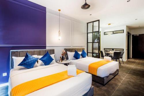 two beds in a room with a table and chairs at Scarletz Service Suites KLCC in Kuala Lumpur