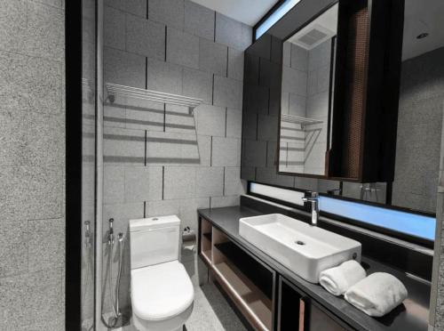 a bathroom with a toilet and a sink and a mirror at Scarletz Service Suites KLCC in Kuala Lumpur