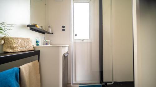 Camping des Alberes في Laroque-des-Albères: حمام مع نافذة وباب مع مناشف