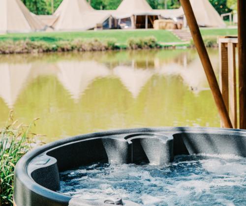 a bath tub filled with water next to a body of water at Teal Safari Tent in Droitwich