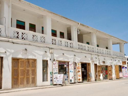 ein weißes Gebäude mit einem Balkon an einer Straße in der Unterkunft Mkunazini Heritage Hostels in Zanzibar City