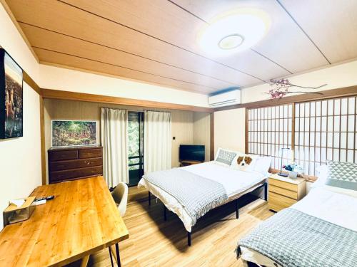 ein Schlafzimmer mit zwei Betten und einem Holztisch in der Unterkunft ZYZ Higashijūjō House in Wada