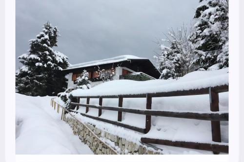 a fence covered in snow in front of a house at Casa nel Bosco in Trento