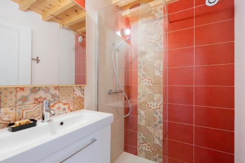 y baño con lavabo y ducha con azulejos rojos. en Nature and vue imprenable, en Ouroux