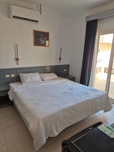 Una cama blanca grande en un dormitorio con ventana. en Elixir Hotel Hurghada, en Hurghada