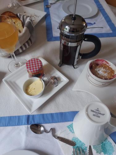 Una mesa con un plato de comida y una taza de café. en Gîte, Le Séchoir à Lin demeure de charme, en Veauville-les-Baons
