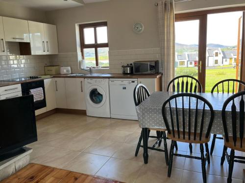 une cuisine avec une table et des chaises et une cuisine avec une machine à laver dans l'établissement Holiday Home Achill Sound Holiday Village No 11 by Interhome, à Achill Sound