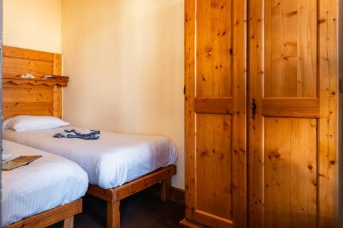 a bedroom with two beds and a wooden closet at Le Cheval Blanc - Village Montana in Val Thorens