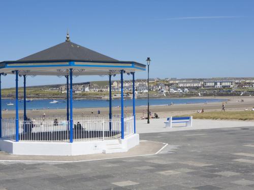 a gazebo at a beach with people on the beach at Holiday Home Moore Bay - TR4 HH No 14A by Interhome in Kilkee