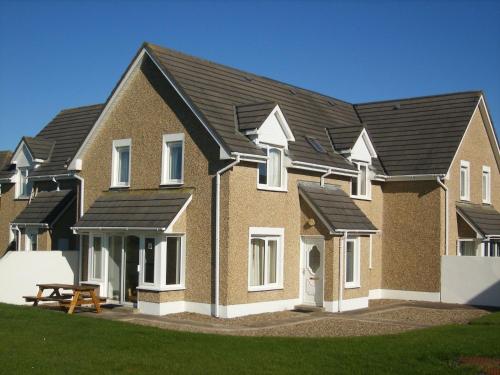 a large brick house with black roof at Holiday Home Moore Bay - TR4 HH No 14A by Interhome in Kilkee