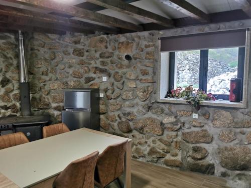 a room with a stone wall with a table and a window at Casa Olho da Lebre Barrocal in Trancoso