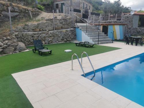 a swimming pool with a bench and a table and chairs at Casa Olho da Lebre Barrocal in Trancoso