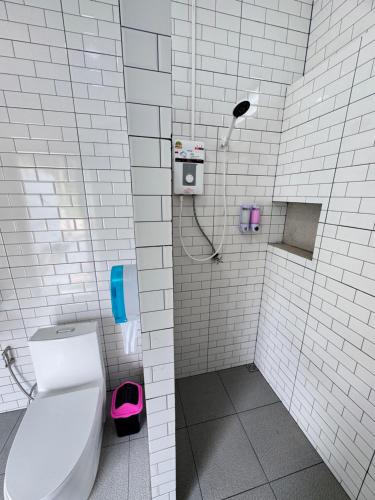 a white tiled bathroom with a toilet and a shower at Seaview phuwamin in Phra Ae beach