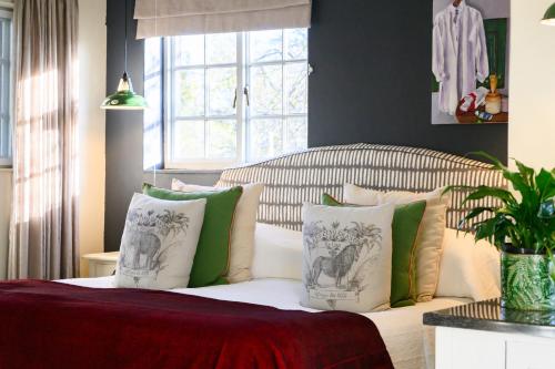 a bedroom with a bed with green and white pillows at Baruch Guesthouse on Lovell in Stellenbosch