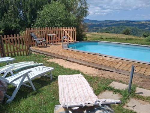 una piscina con terrazza in legno, tavolo e sedie di Gîte Le Duzon a Plats
