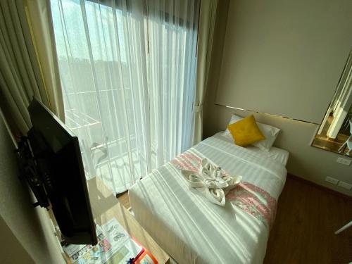 a room with a bed and a television and a window at Phu Dahla Apartments in Ban Khlong Haeng