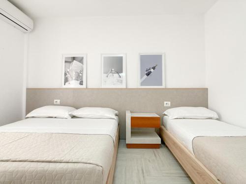 two beds in a room with three pictures on the wall at Nest at the beach in Golem