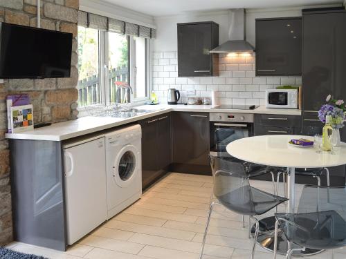 a kitchen with a washing machine and a table at Gracelands in Uny Lelant