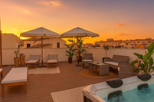 a deck with a hot tub and chairs and umbrellas at Hotiday Apartments Siracusa in Syracuse