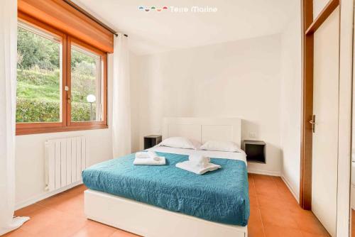una camera da letto con un letto con lenzuola blu e una finestra di LunaMare, Terre Marine a Santo Stefano di Magra
