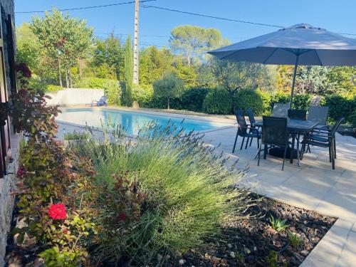 un patio con mesa y sombrilla junto a la piscina en Holiday Home Les Pierres Fleuries by Interhome, en Trans-en-Provence