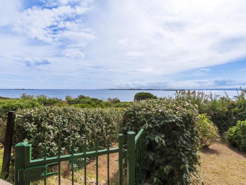 ein grüner Zaun mit dem Ozean im Hintergrund in der Unterkunft Holiday Home Villa 12 by Interhome in SantʼAmanza