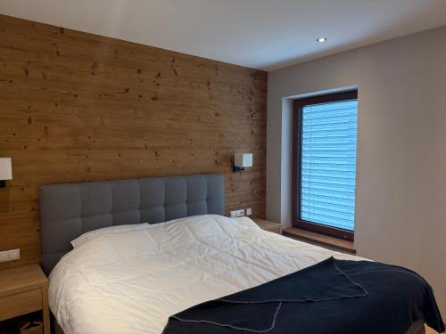 a bedroom with a large bed with a wooden wall at Haus Schlatti in Altenmarkt im Pongau