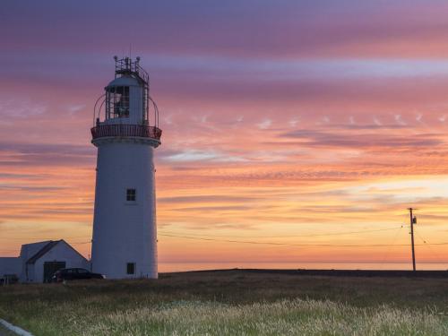 un phare dans un champ avec un coucher de soleil en arrière-plan dans l'établissement Holiday Home Kilkee HH - GF - - S5 - TR1 Type B - No 907 by Interhome, à Kilkee