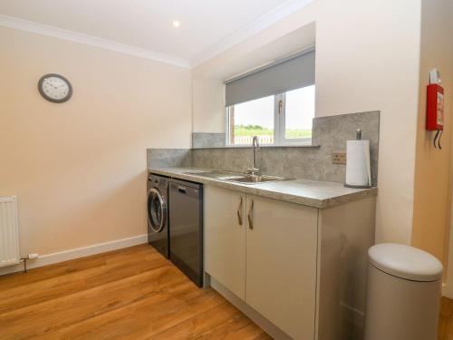 a kitchen with a sink and a washing machine at Bankhead Of Lour Cottage in Kingsmuir