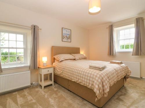 a bedroom with a bed and two windows at Bankhead Of Lour Cottage in Kingsmuir