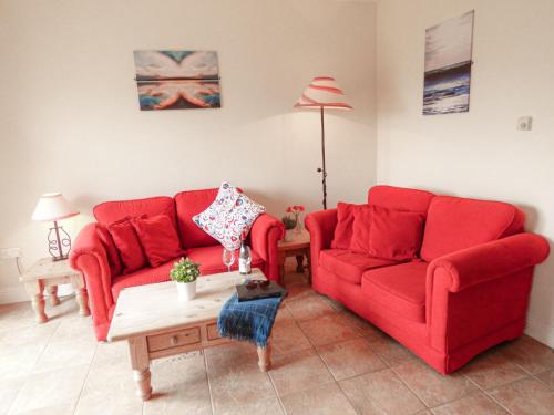 un salon avec deux canapés rouges et une table dans l'établissement Holiday Home Kilkee HH - GF - TR1 Type C - No 903 by Interhome, à Kilkee