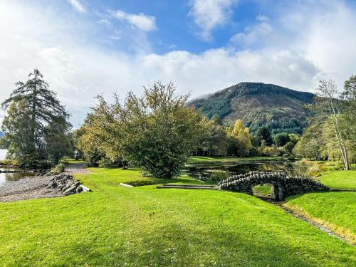 a grassy field with a river and a mountain at Holiday Home The Romantic Bothy by Interhome in Invermoriston