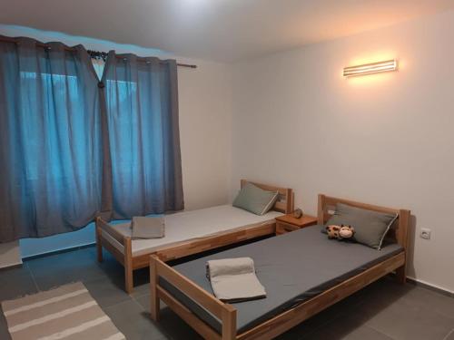 two beds in a room with blue curtains at Lena Apartman in Senta